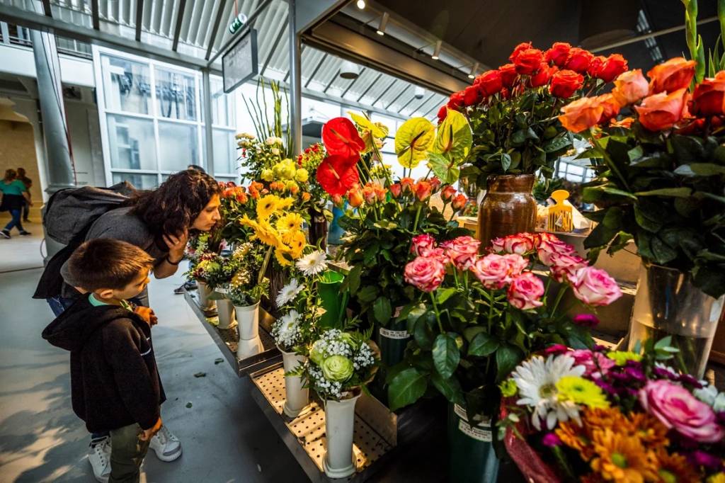 BOLHAOGUILHERMECOSTA2 Mãe e filho observam flores coloridas numa banca de mercado