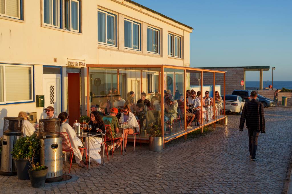 _1NC8979 Varanda de um restaurante com mesas lotadas e uma luz de por do sol